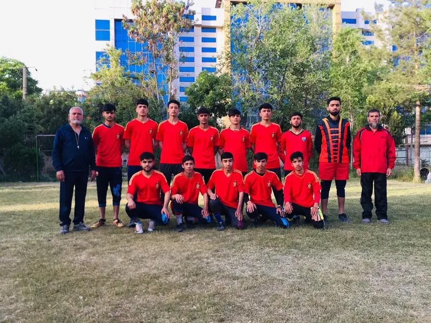 The school sports team and coach in red kit on the grass