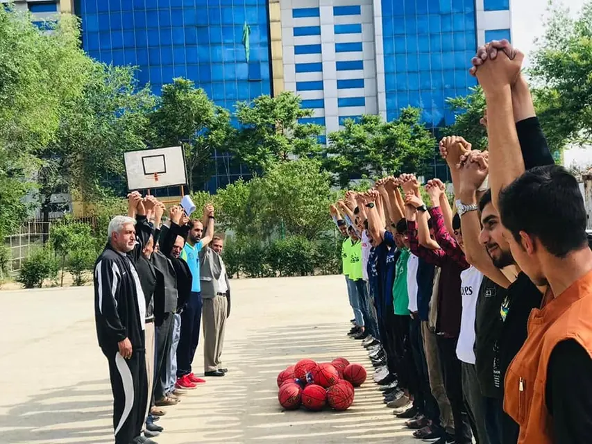 Teachers and students raising joined hands at the start of a game