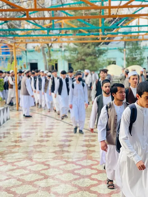 Students in white uniforms walking through the courtyard